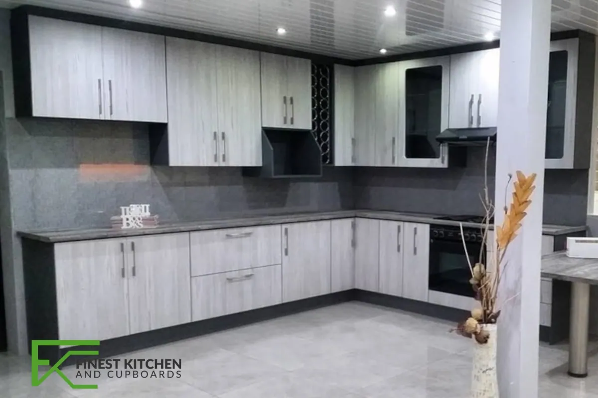 An L-shaped FKC kitchen in light timber and white with a black oven stack.