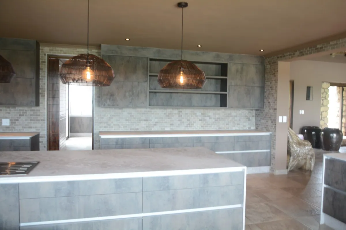 The island under construction, with a concrete-look base, marble splashback and copper pendants already hung.